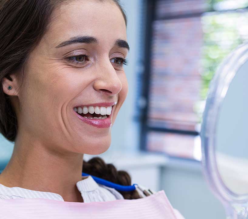 patient-smiling-while-looking-at-mirror-in-dental